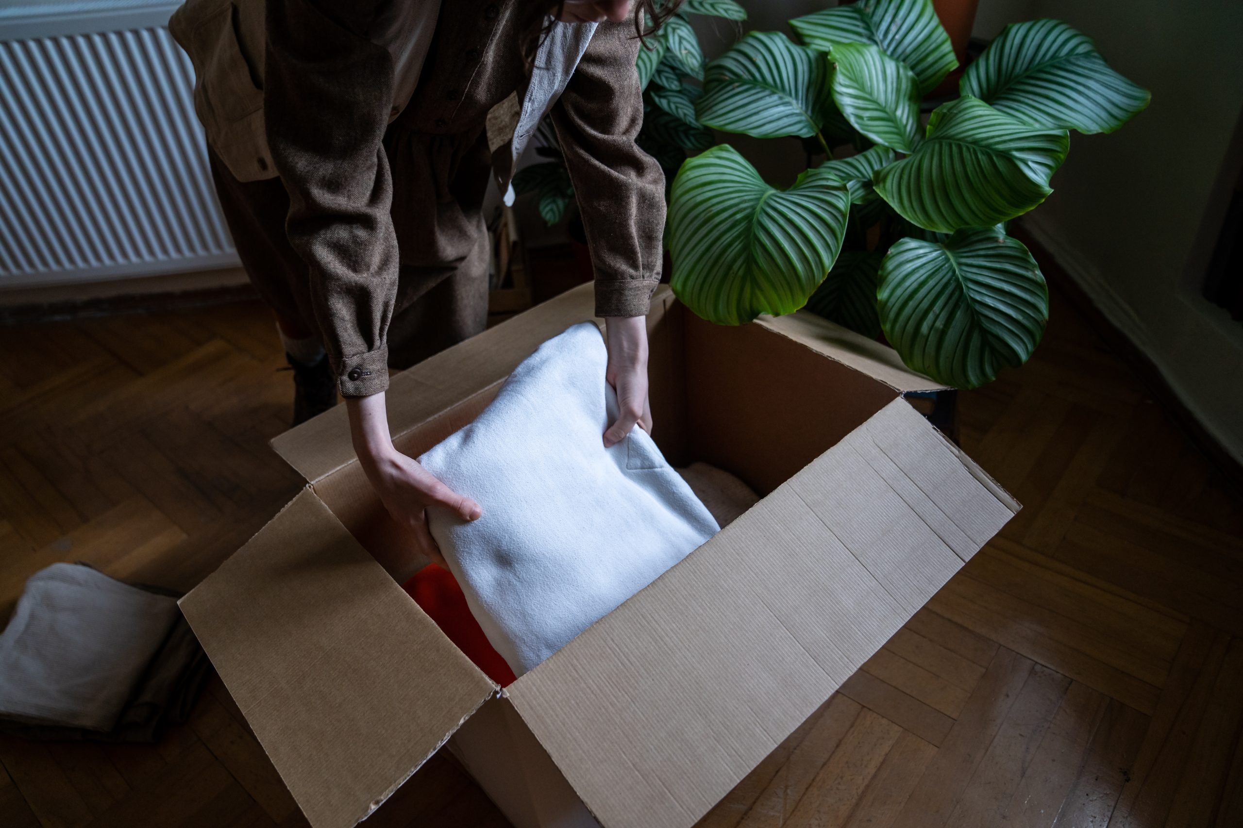 Woman stacking putting clothes in cardboard box preparing for moving